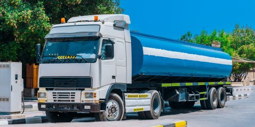 Water tank trailer unit, prime mover, refuel at gas and oil station in sunny summer day. Water tank trailer parked near oil station. Water tank trailer unit, prime mover, refuel at gas and oil station in sunny summer day.